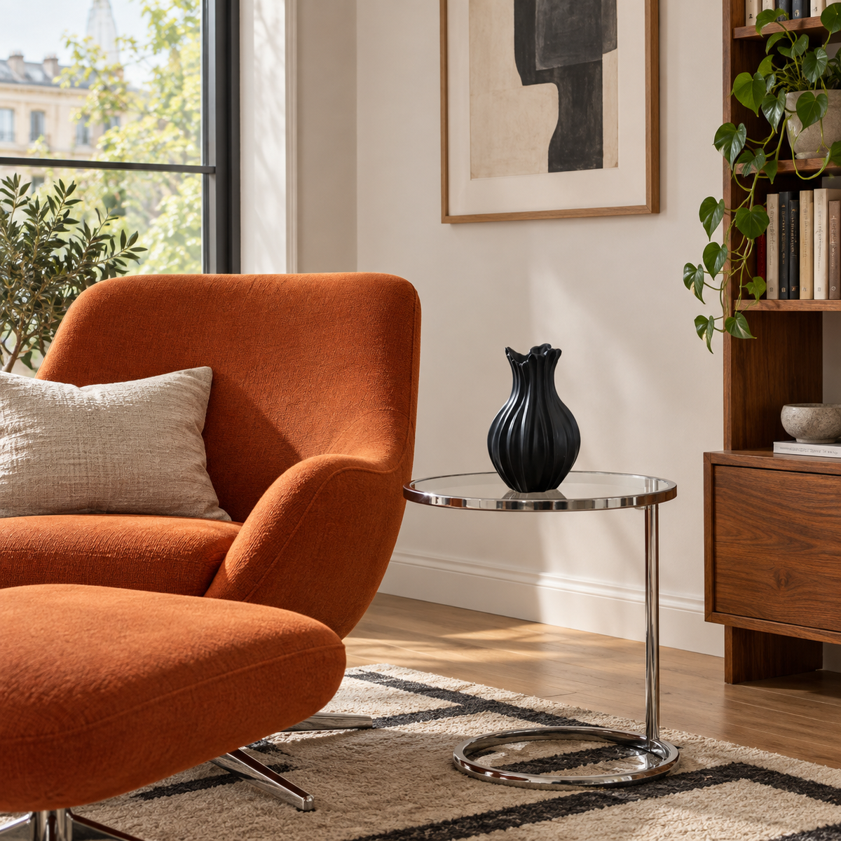 Mattschwarze Keramikvase mit tiefen Rillen leer auf einem Glasbeistelltisch neben einem orangefarbenen Sessel.