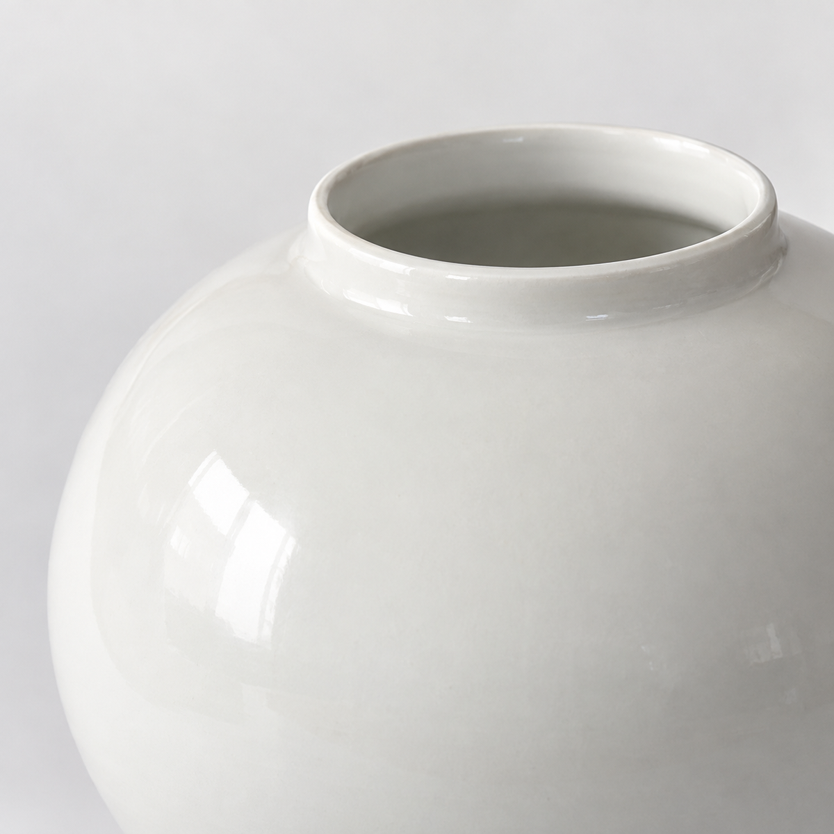 Small glossy white moon ceramic vase: short rim, rounded shoulder and smooth white glaze.