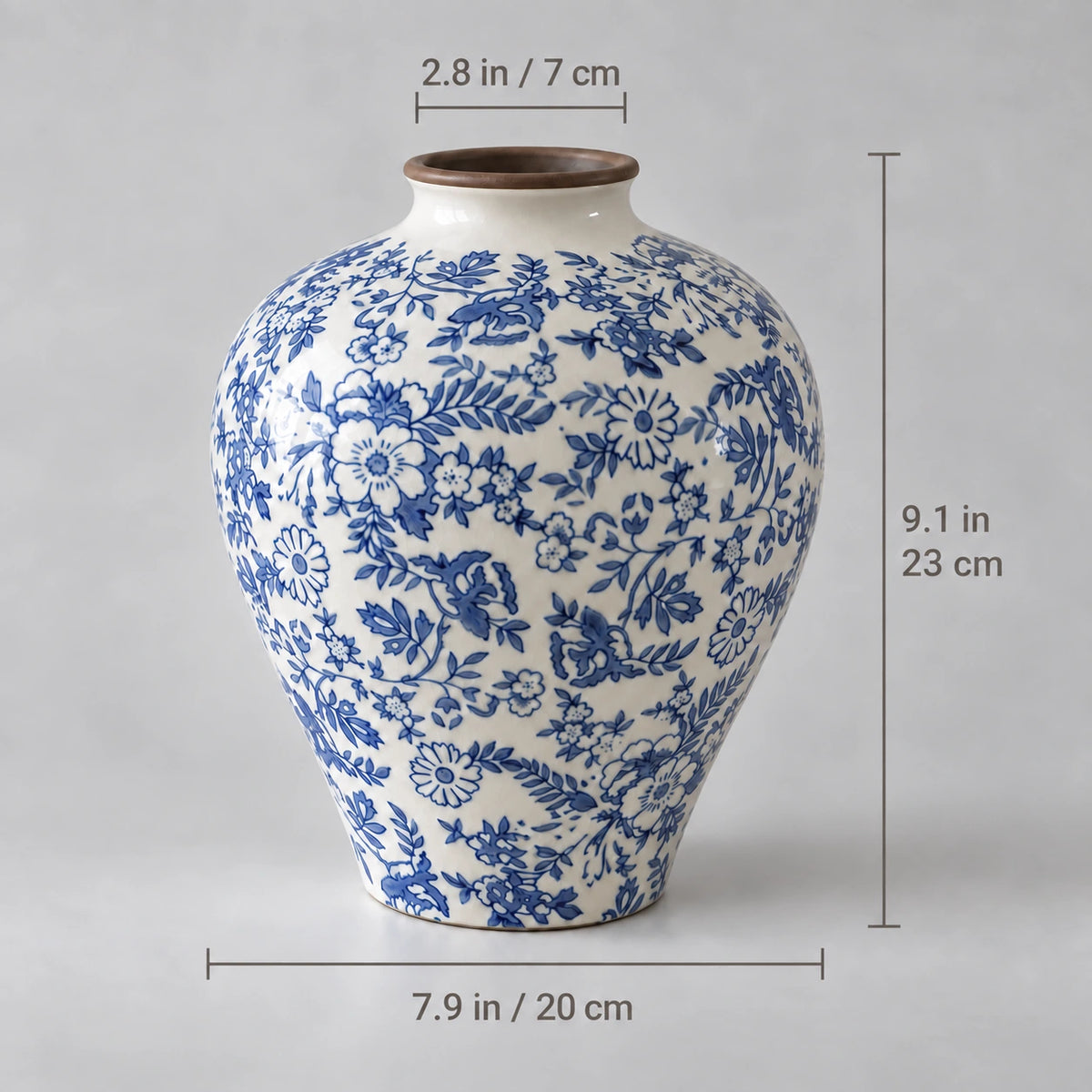 Blue and white floral vase measuring 23 cm high, 20 cm wide and 7 cm across the opening, with inch equivalents.