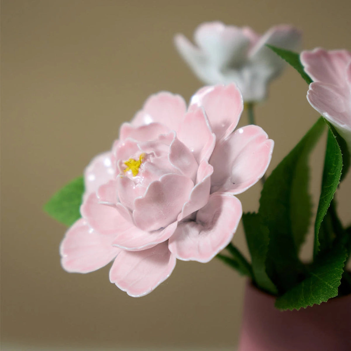 Close view of layered pink porcelain petals with glossy edges and a small yellow centre.