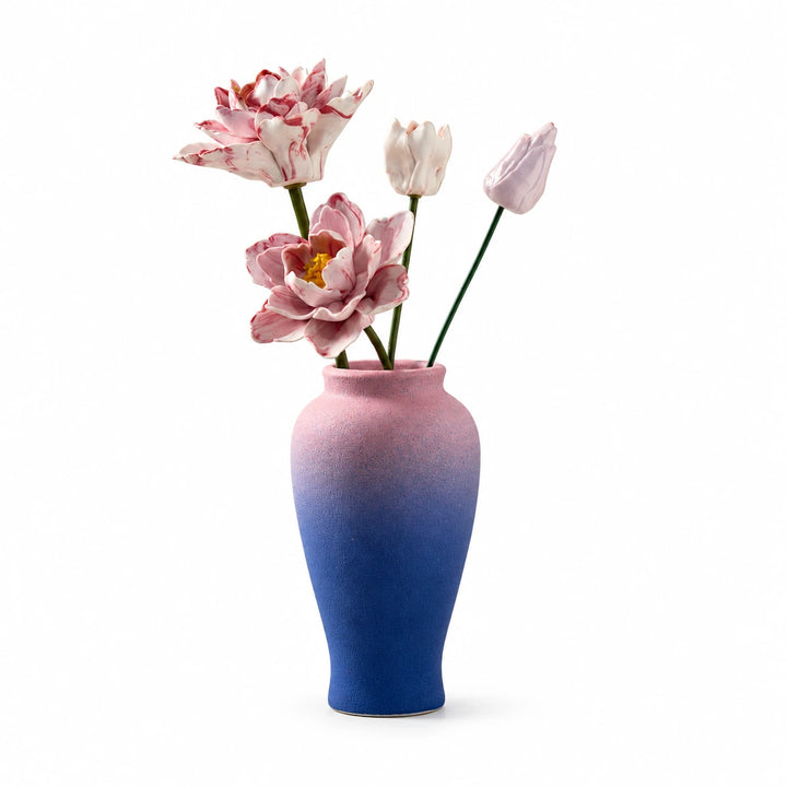 Two open pink flowers and two smaller buds in a textured pink-and-blue vase on a white background.