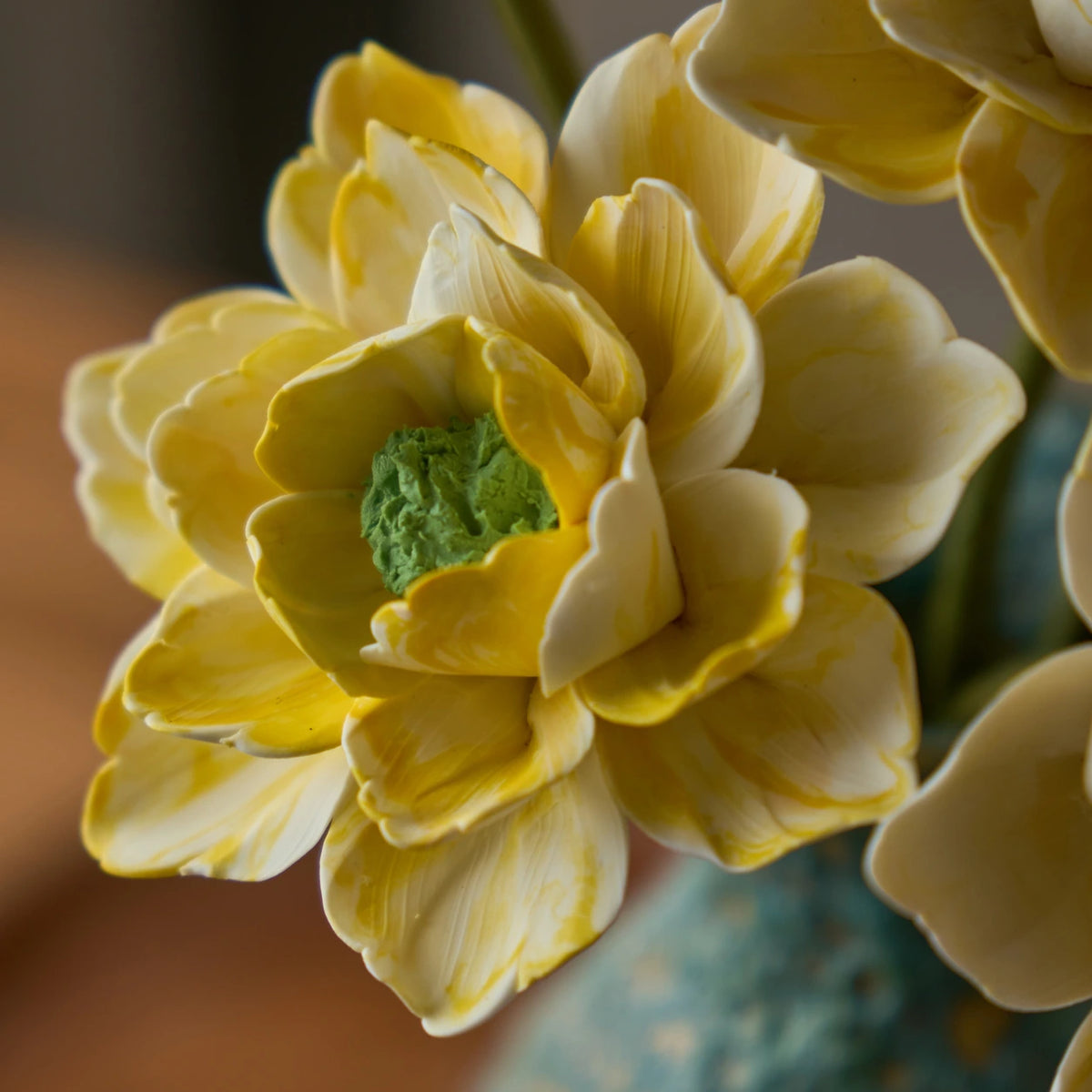 Close view of cream-yellow sculpted ceramic petals with a textured green flower centre.