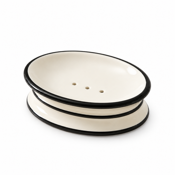 Ivory oval ceramic soap dish with black trim and three drainage holes.