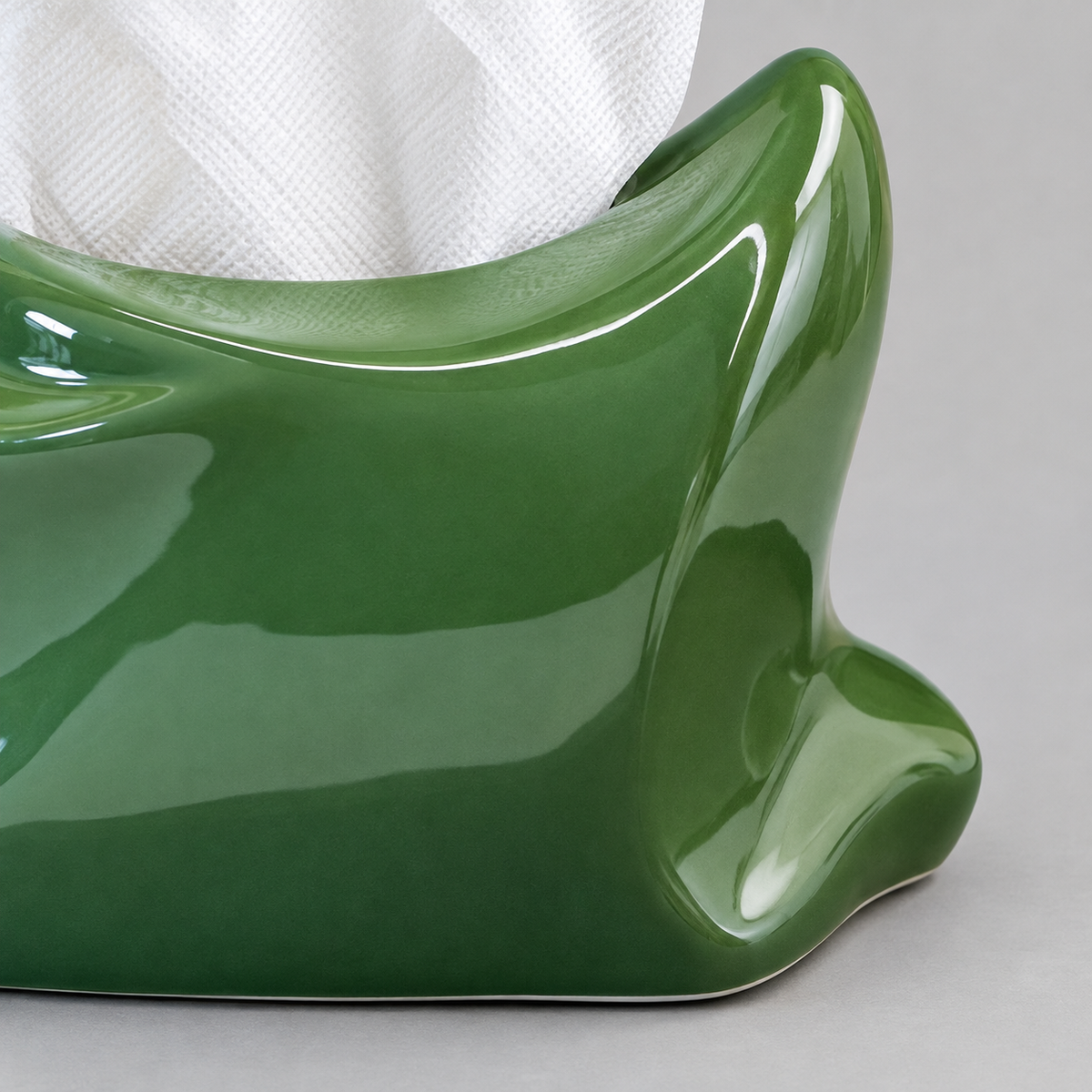 Close view of the green ceramic tissue cover’s glossy curled corner and tissue opening