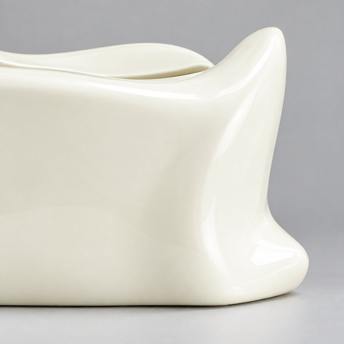 Close view of the cream-white ceramic tissue cover’s curved lip and folded corner