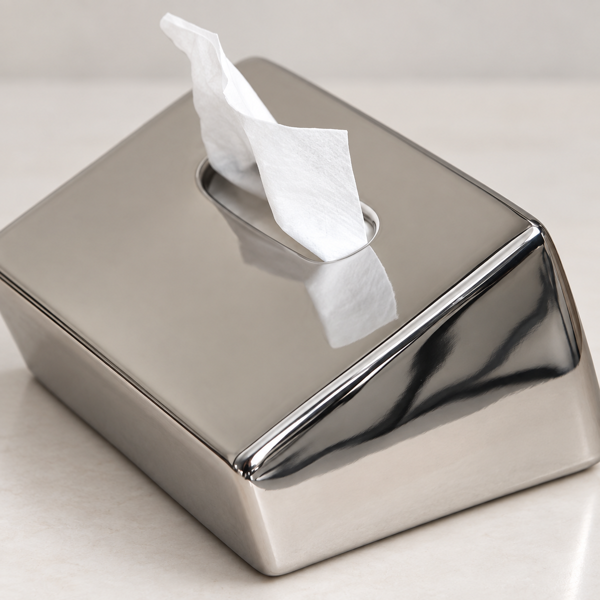 Close view of the mirror-silver tissue cover’s sloping ceramic surface and rounded opening