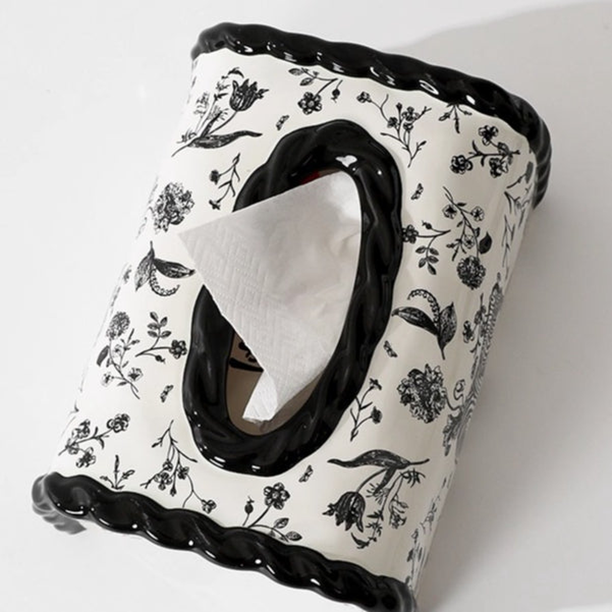 Original black ceramic cover photo showing the glossy twisted oval opening, tissue and botanical print.