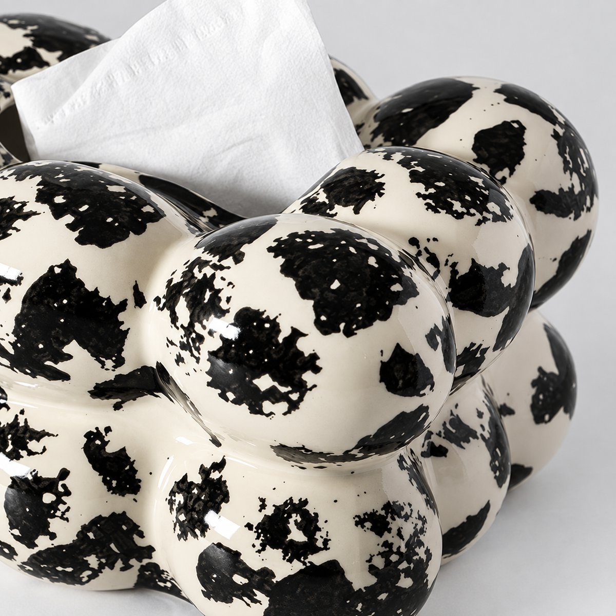 Close view of black ink-like patches and glossy ivory glaze on the rounded bubble surface
