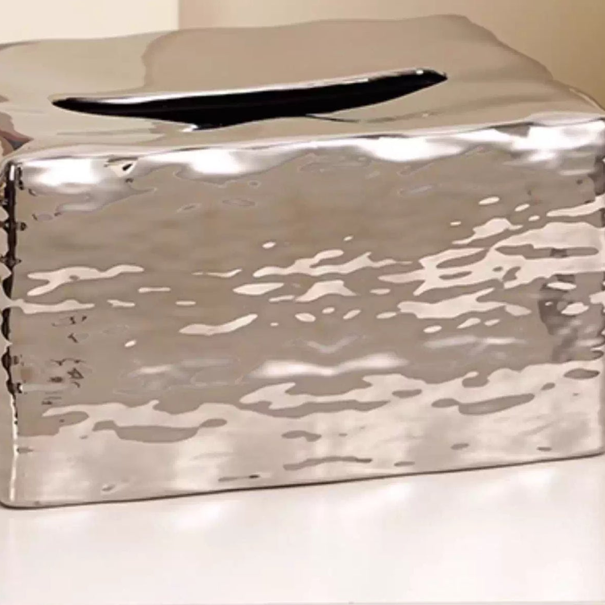 Close view of the Liquid Mirror Silver tissue cover’s elongated top slot and irregular silver reflections.