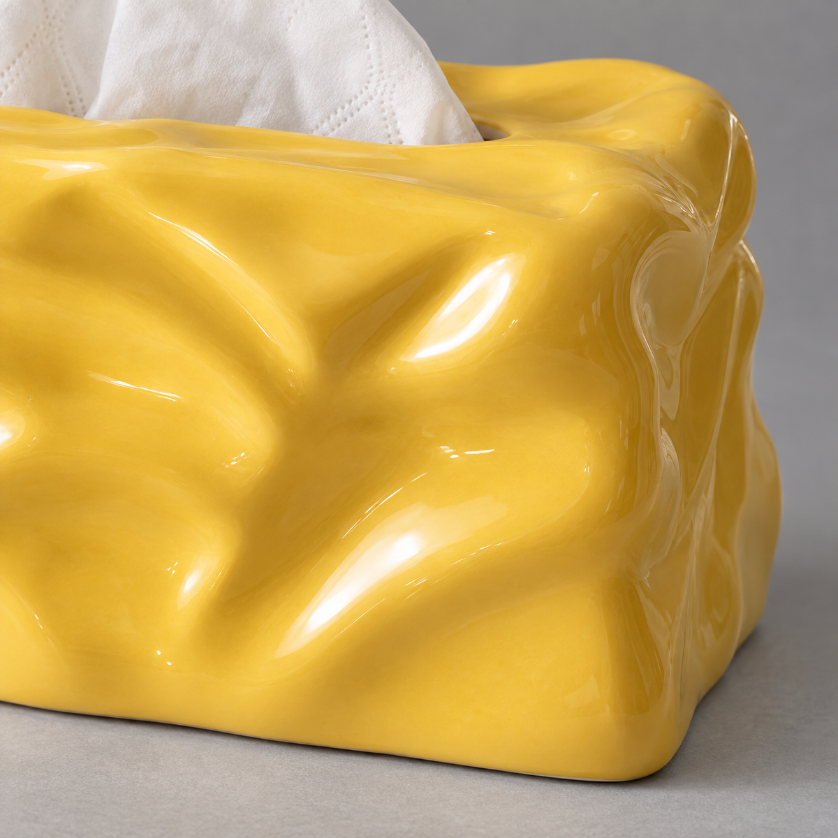 Close view of the yellow tissue cover’s sculpted folds and glossy ceramic surface