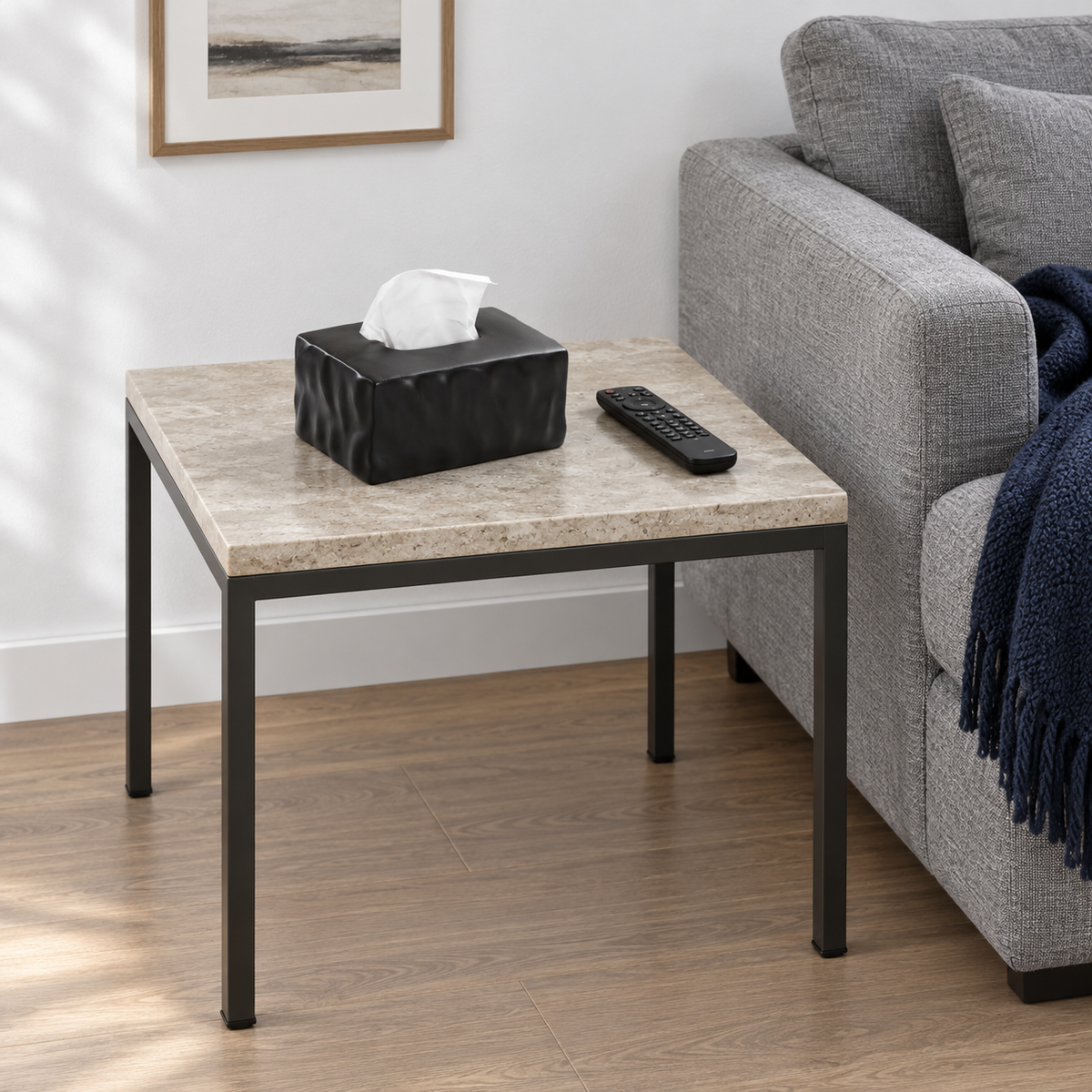 Matte Noir tissue box cover on a stone-topped side table beside a grey sofa and remote control.