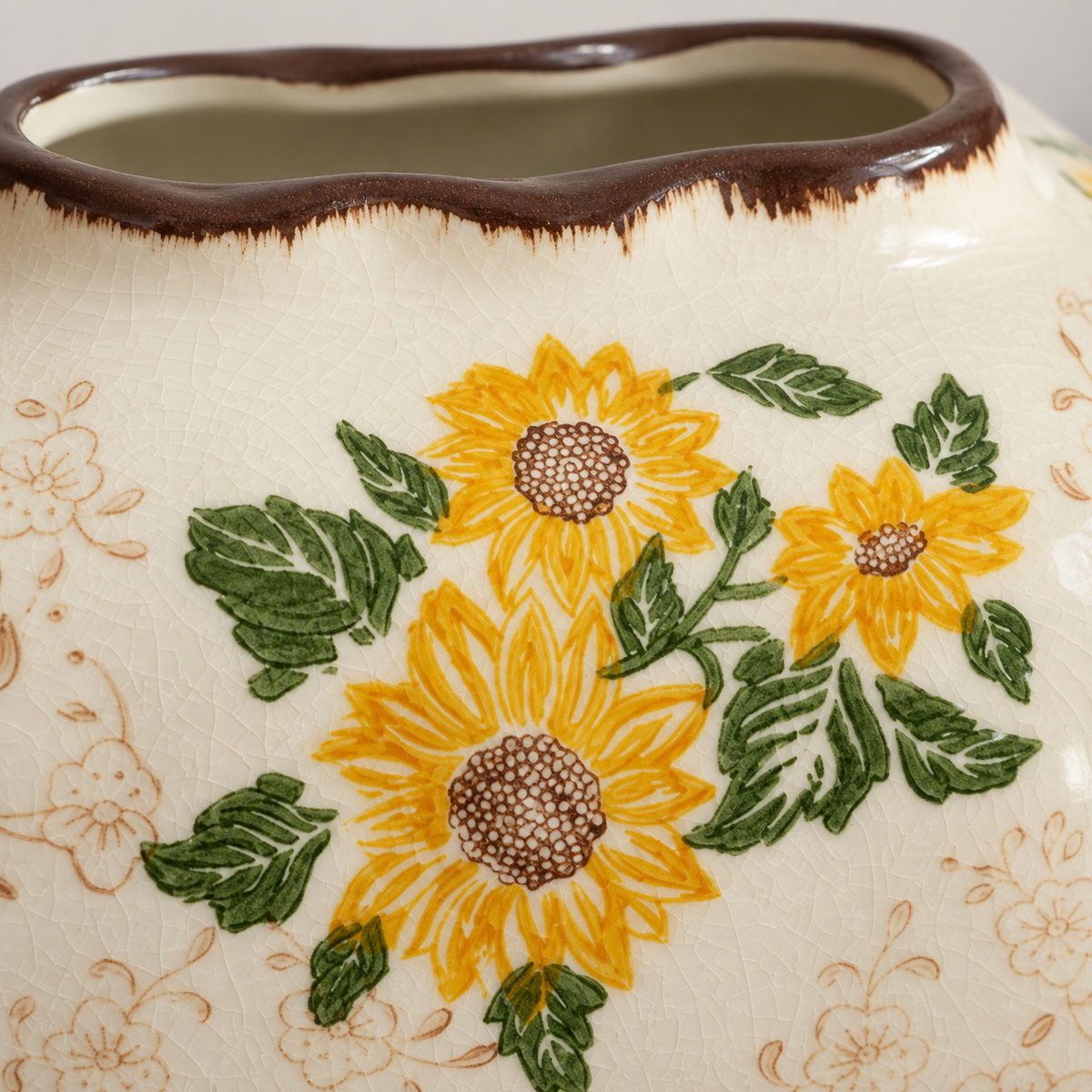 Close view of yellow sunflowers, green leaves, fine crackle glaze and the brown opening rim.