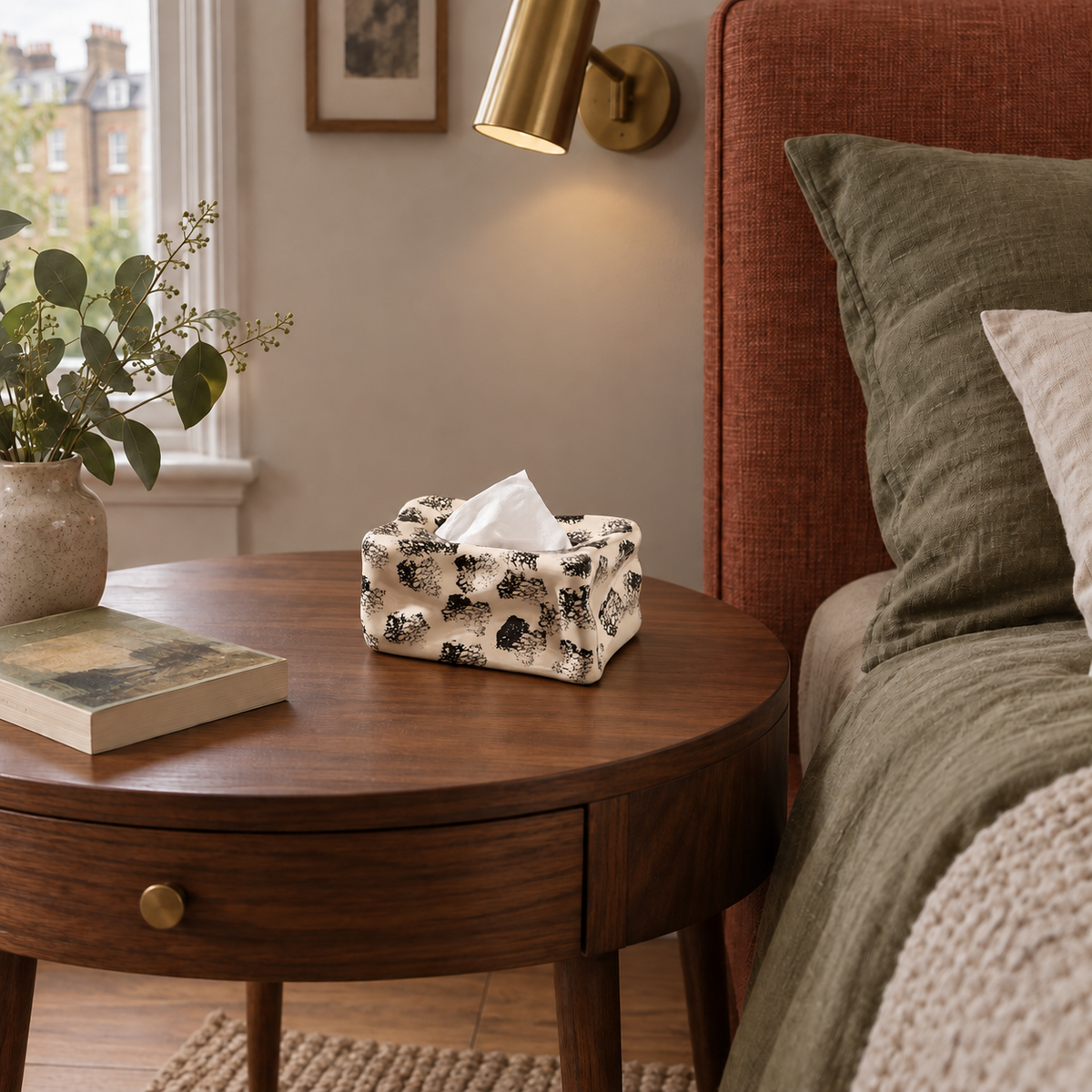 Ivory ink-spot ceramic tissue cover on a walnut bedside table in a bedroom.