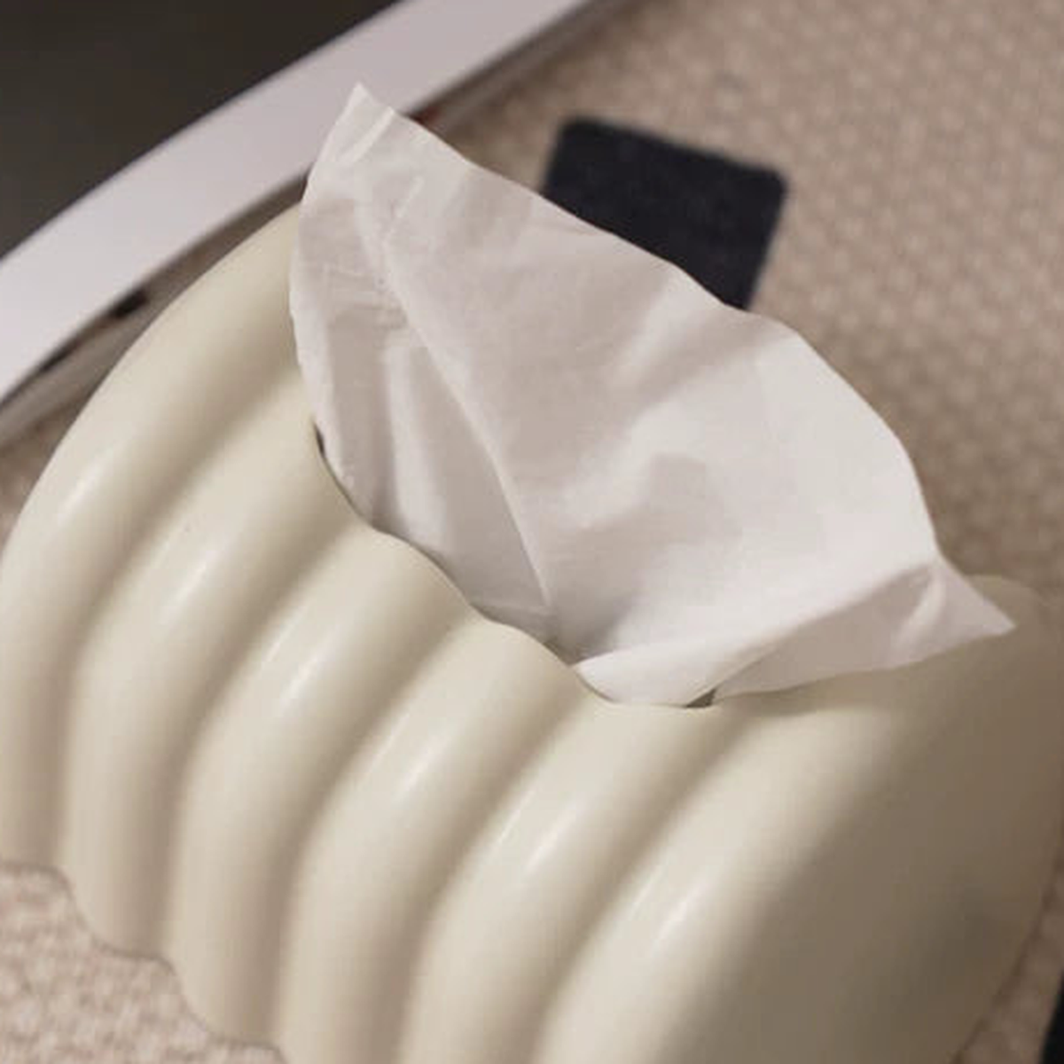 Overhead close view of the cream ceramic cover’s rounded ribs and central tissue outlet.