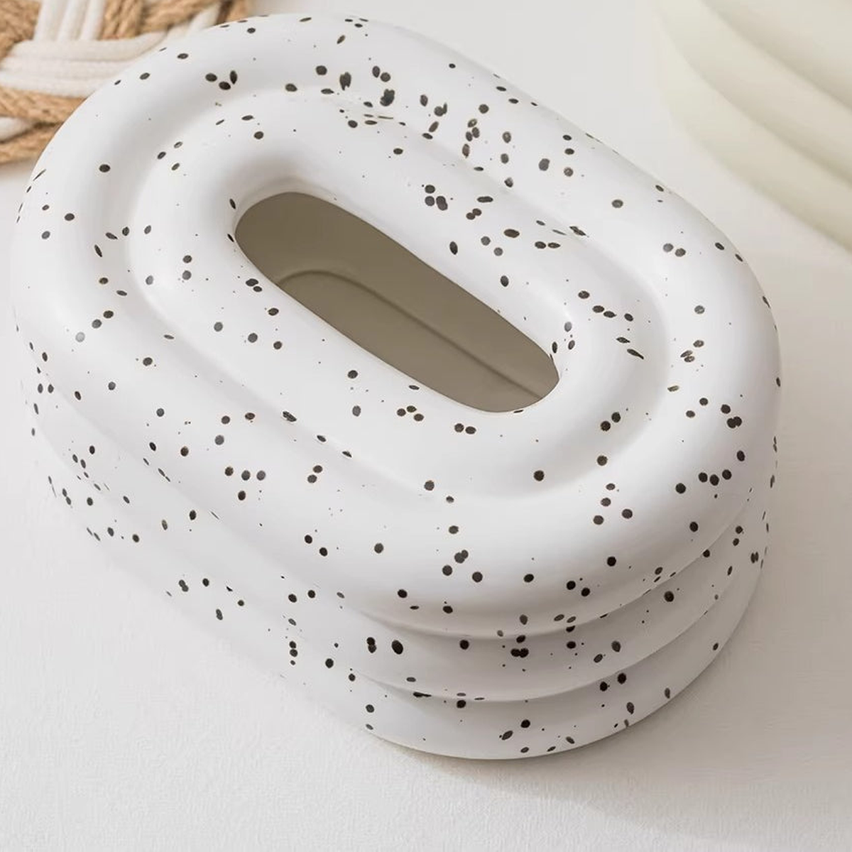Close view of the speckled ceramic finish, thick rounded tiers and oval tissue outlet.