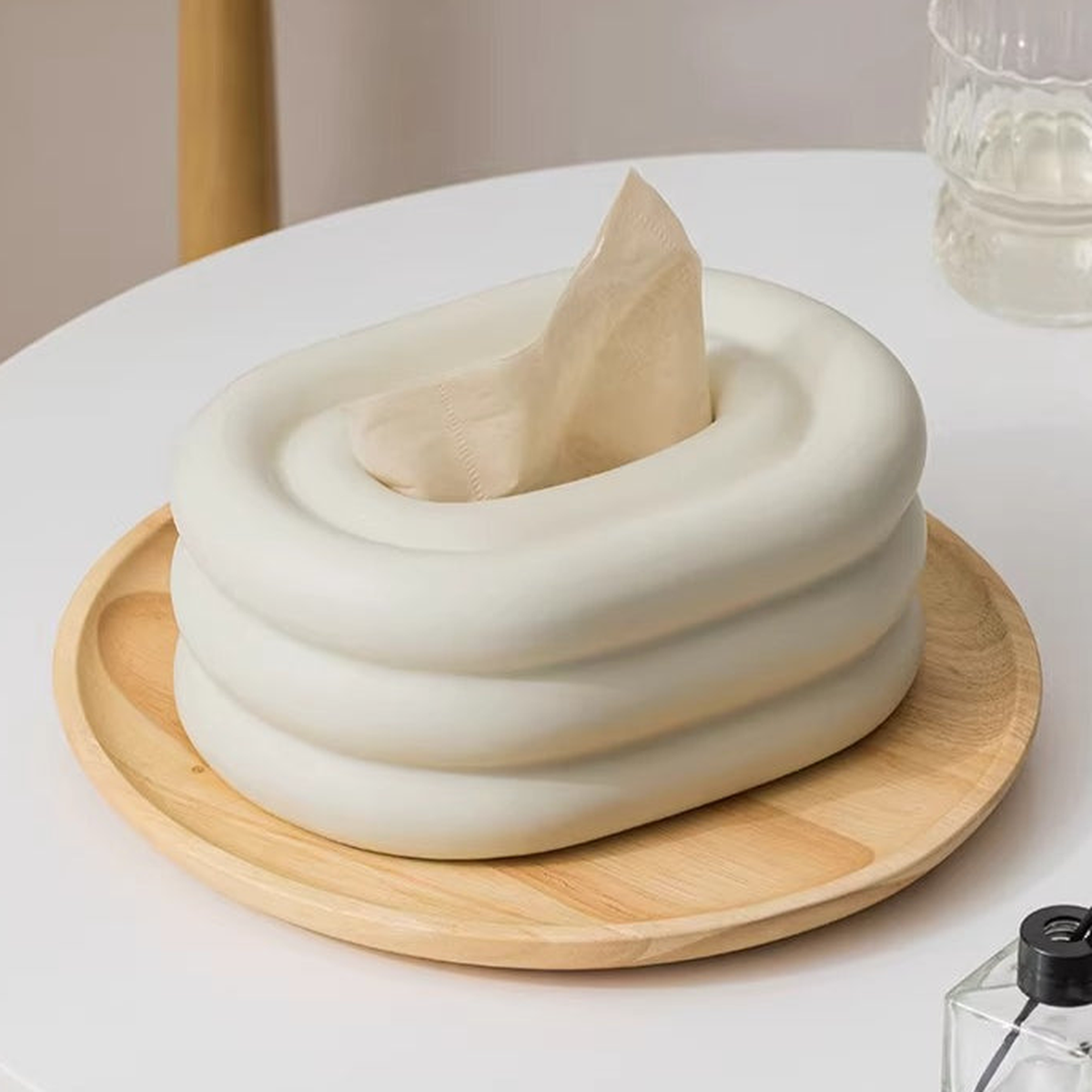 Close view of the plain warm-ivory ceramic tiers and tissue outlet on a wood tray.