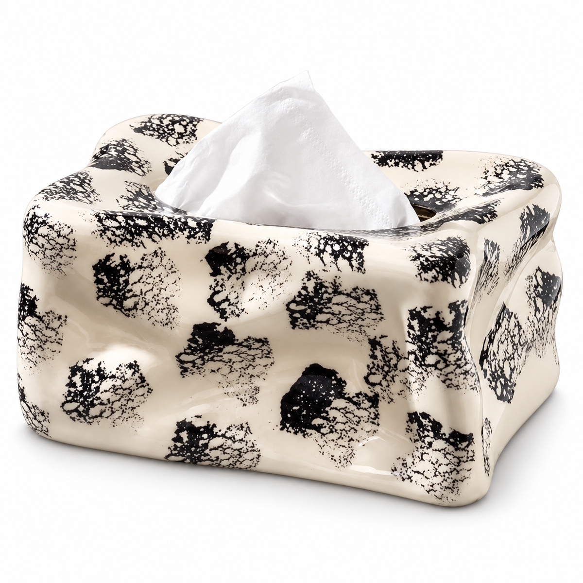 Cream ceramic tissue box cover with black ink spots, an irregular wavy body and a white tissue.