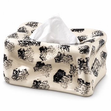Cream ceramic tissue box cover with black ink spots, an irregular wavy body and a white tissue.