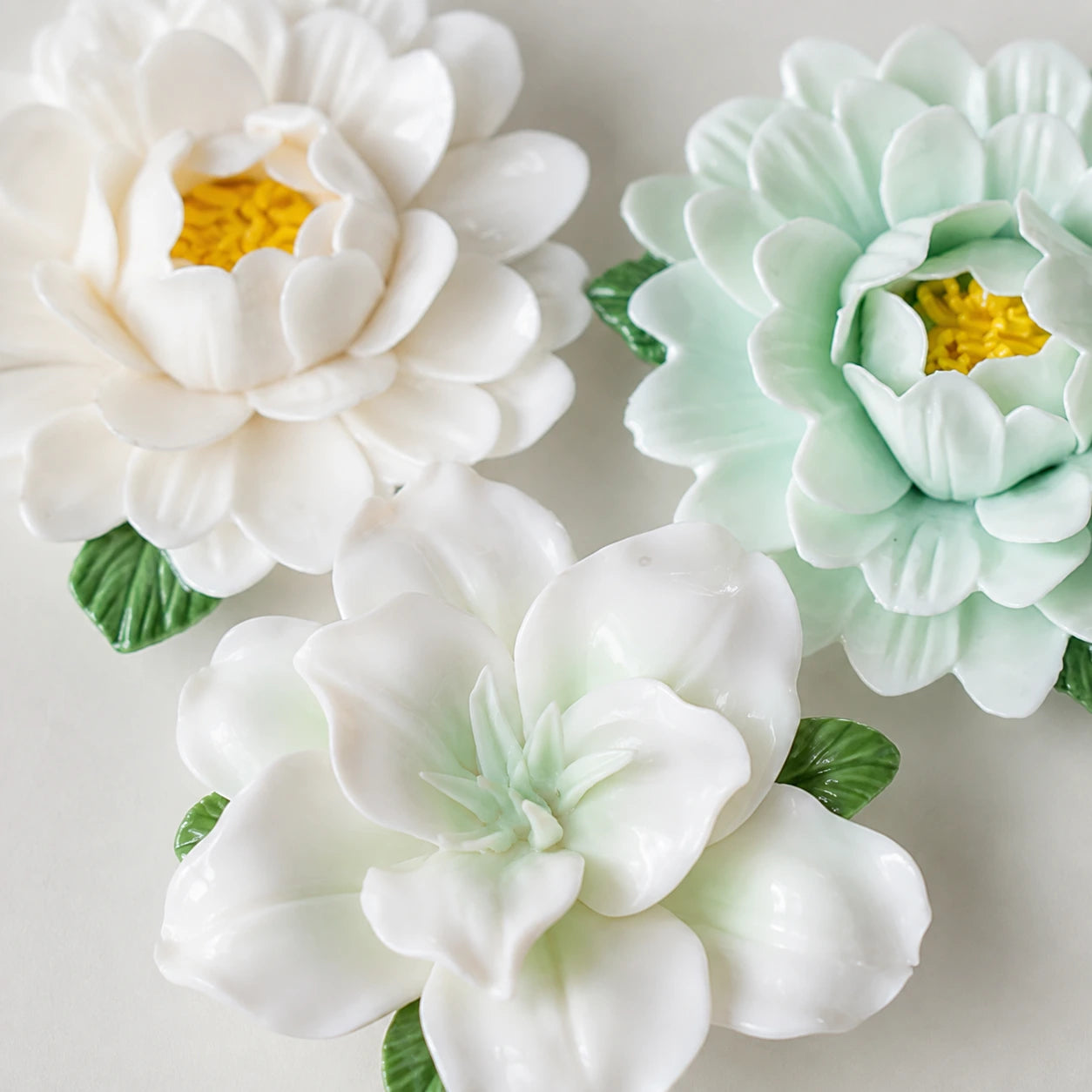 Close-up of Sage & Ivory ceramic flowers, showing pale-green lily folds and layered white and mint peony petals.