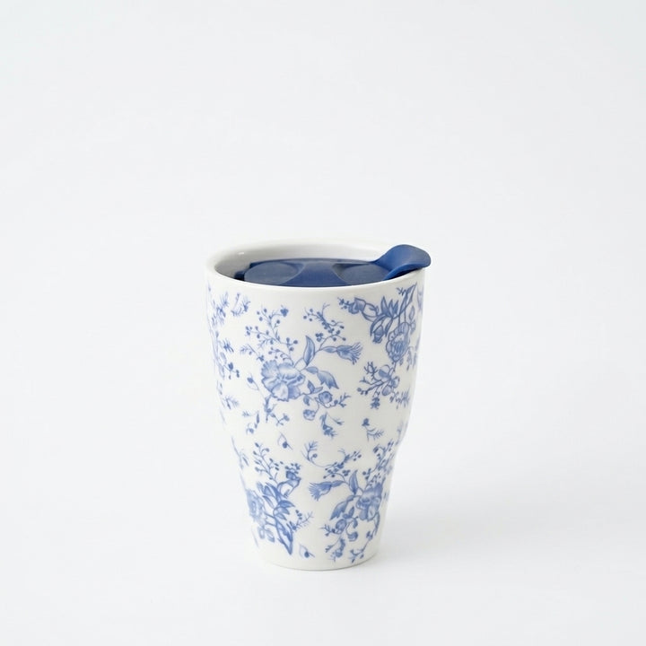 Blue botanical ceramic travel mug with navy sliding lid on a white background