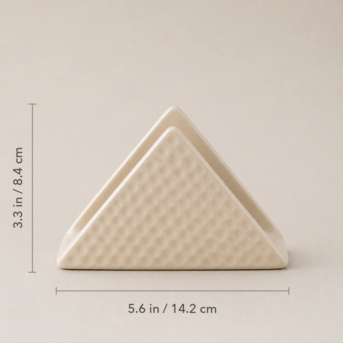 Front view of beige ceramic napkin holder marked 5.6 inches wide and 3.3 inches high