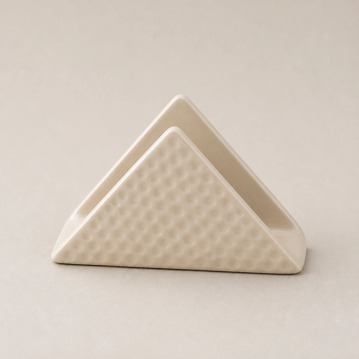 Light beige triangular ceramic napkin holder with dimpled outer panels