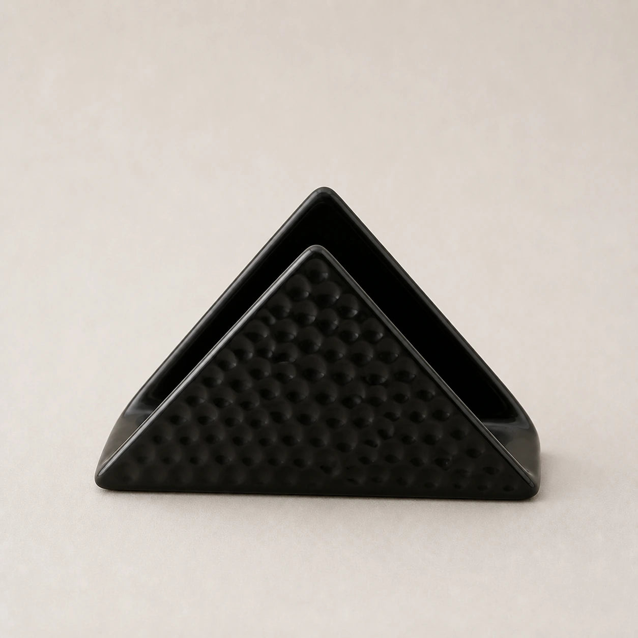 Black triangular ceramic napkin holder with dimpled outer panels