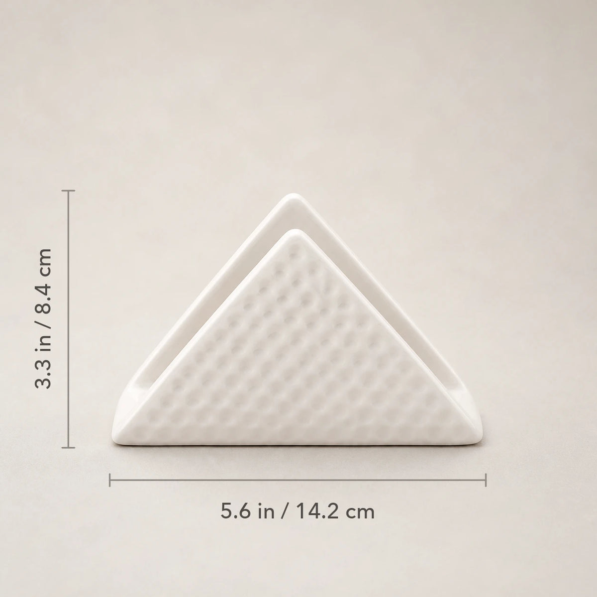 Front view of white ceramic napkin holder marked 5.6 inches wide and 3.3 inches high