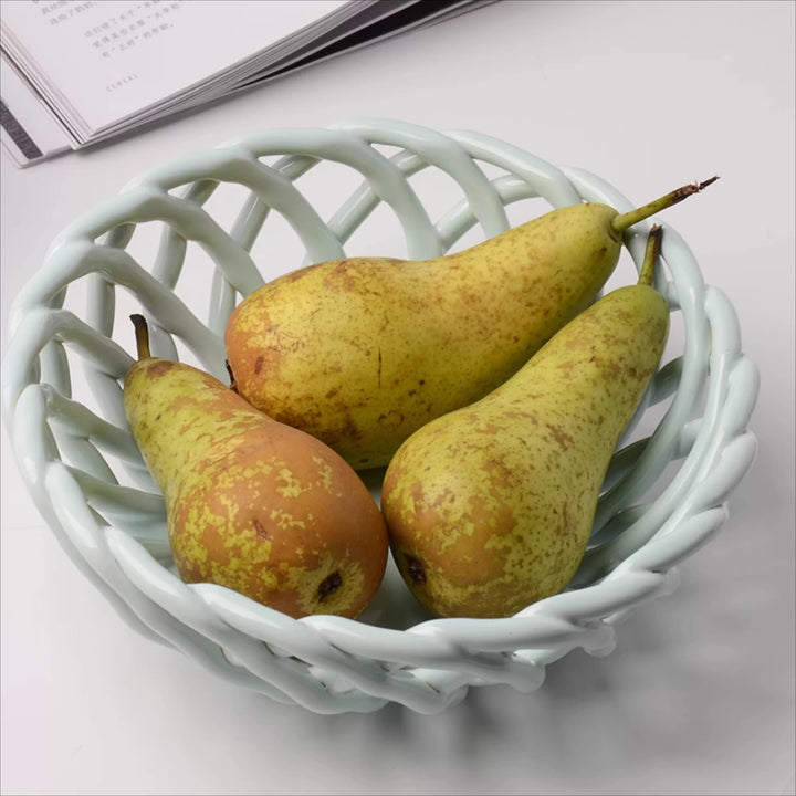 Pale blue open-lattice ceramic fruit bowl with looping sides and a braided rim, holding three green pears.
