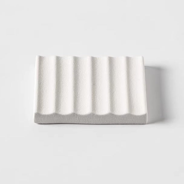 White rectangular ceramic soap dish featuring raised parallel wave grooves, shown from a low front angle in studio.