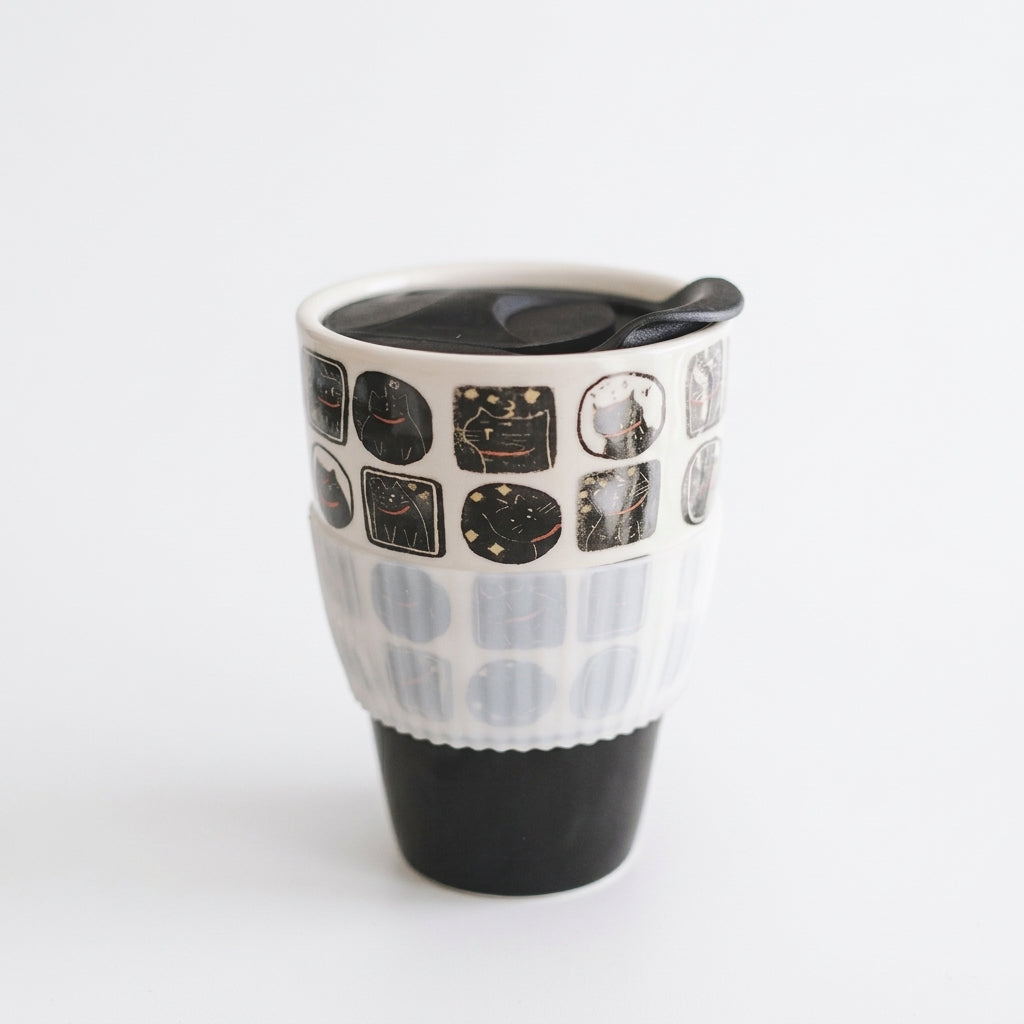 Nocturnal feline ceramic travel mug with black cat panels, black lid and clear sleeve