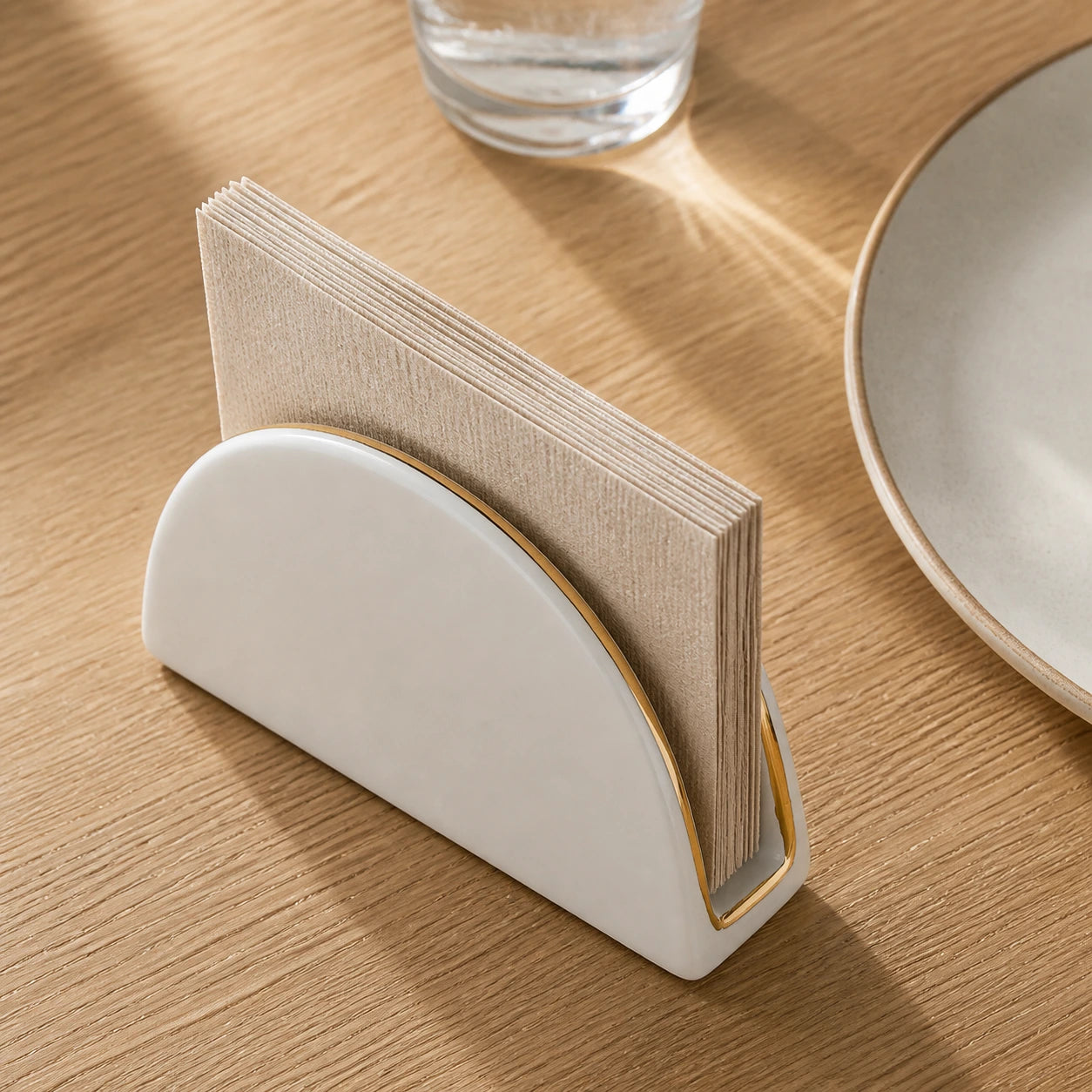 Aufsicht auf den bogenförmigen weißen Keramik-Serviettenhalter mit beigen Papierservietten auf einem Holztisch