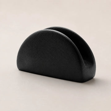 Black ceramic napkin holder with twin rounded arches on a warm neutral background