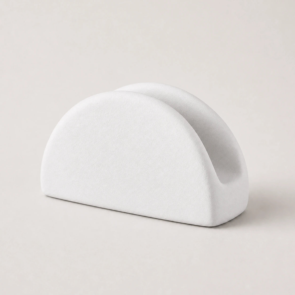 White ceramic napkin holder with twin rounded arches on a warm neutral background
