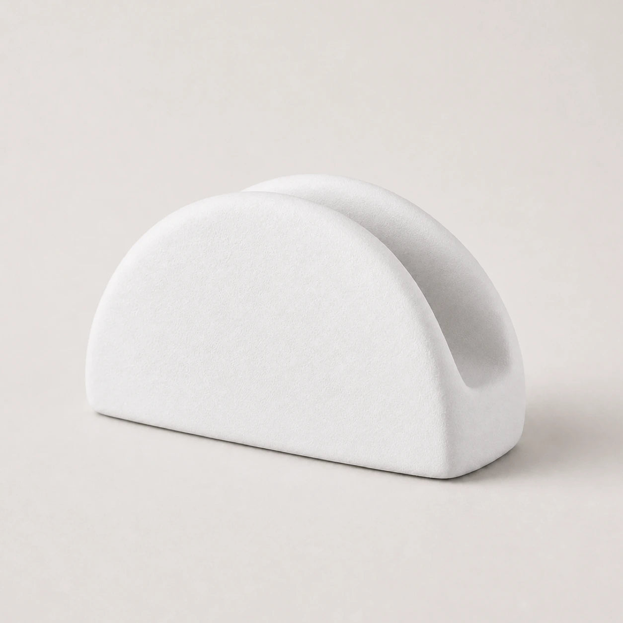 White ceramic napkin holder with twin rounded arches on a warm neutral background