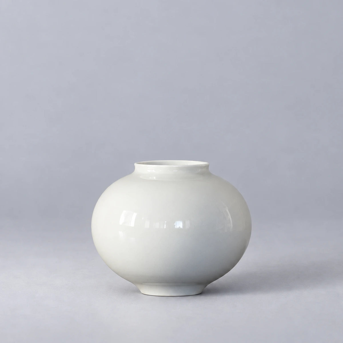 Small glossy white moon vase with a rounded body and short open neck, shown empty on a light grey background.