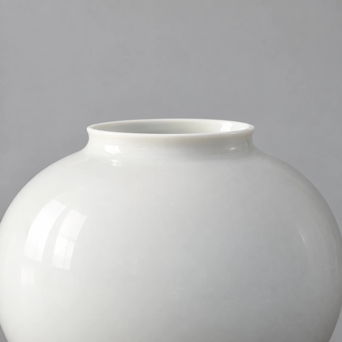 Close view of the small moon vase showing its short flared rim and smooth glossy white ceramic shoulder.
