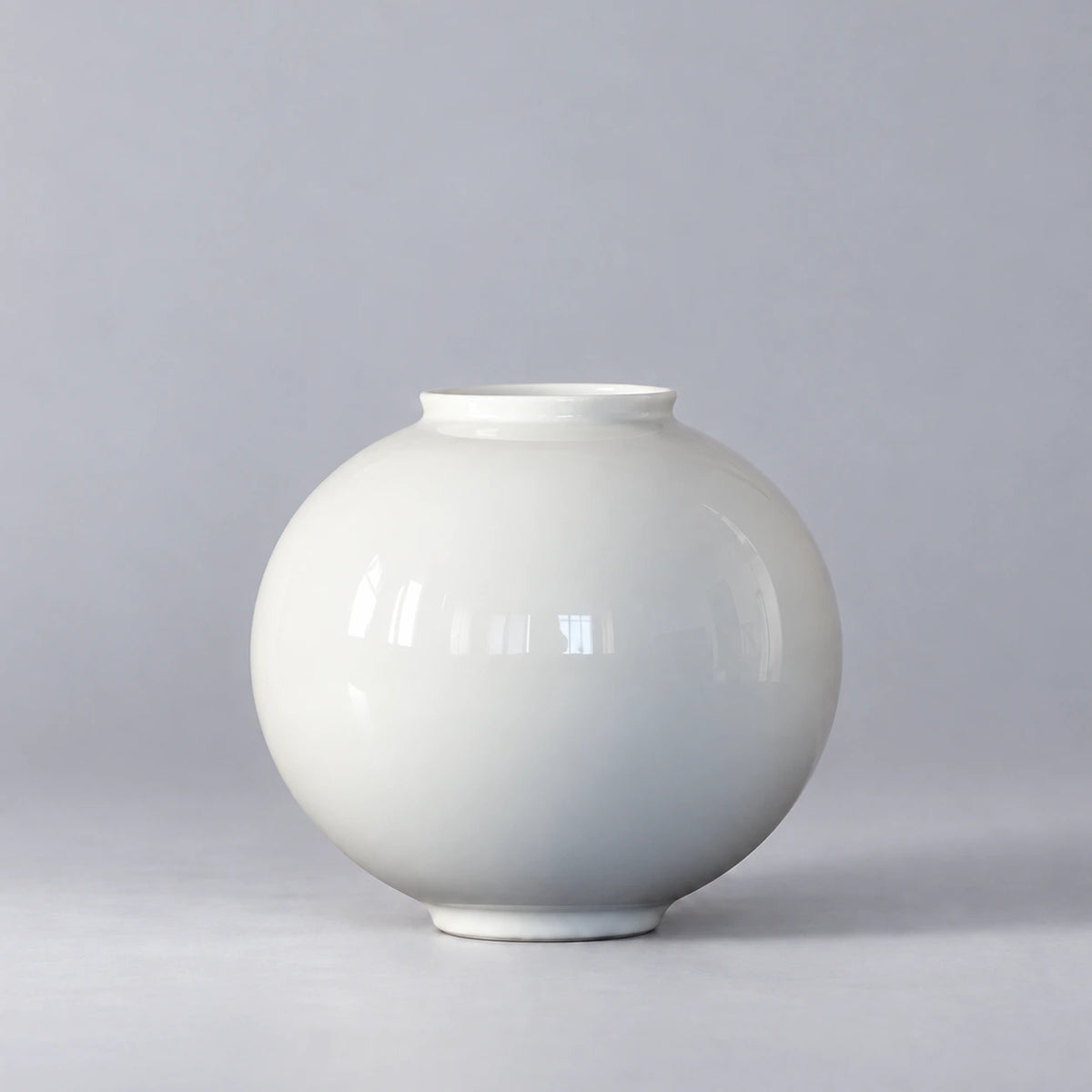 Medium glossy white moon vase with a rounded body and short open neck, shown empty on a light grey background.