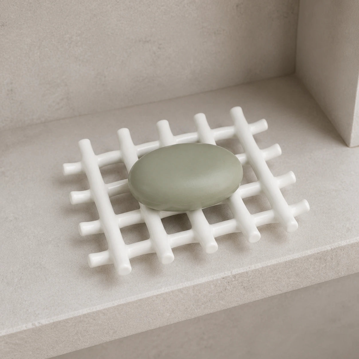 White branch-grid ceramic soap dish with sage soap on a shower shelf