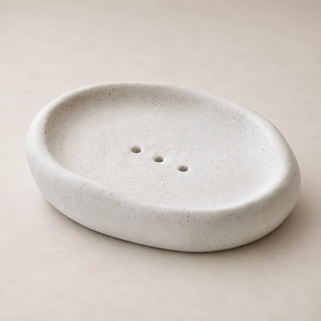 Empty Matte Speckled Cloud ceramic soap dish on pale warm stone