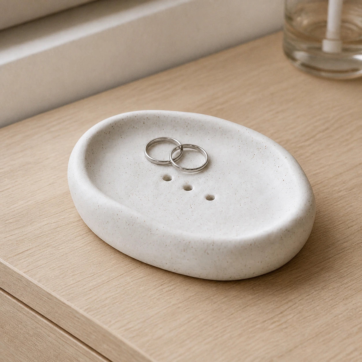 Matte Speckled Cloud ceramic dish holding two silver rings on a vanity