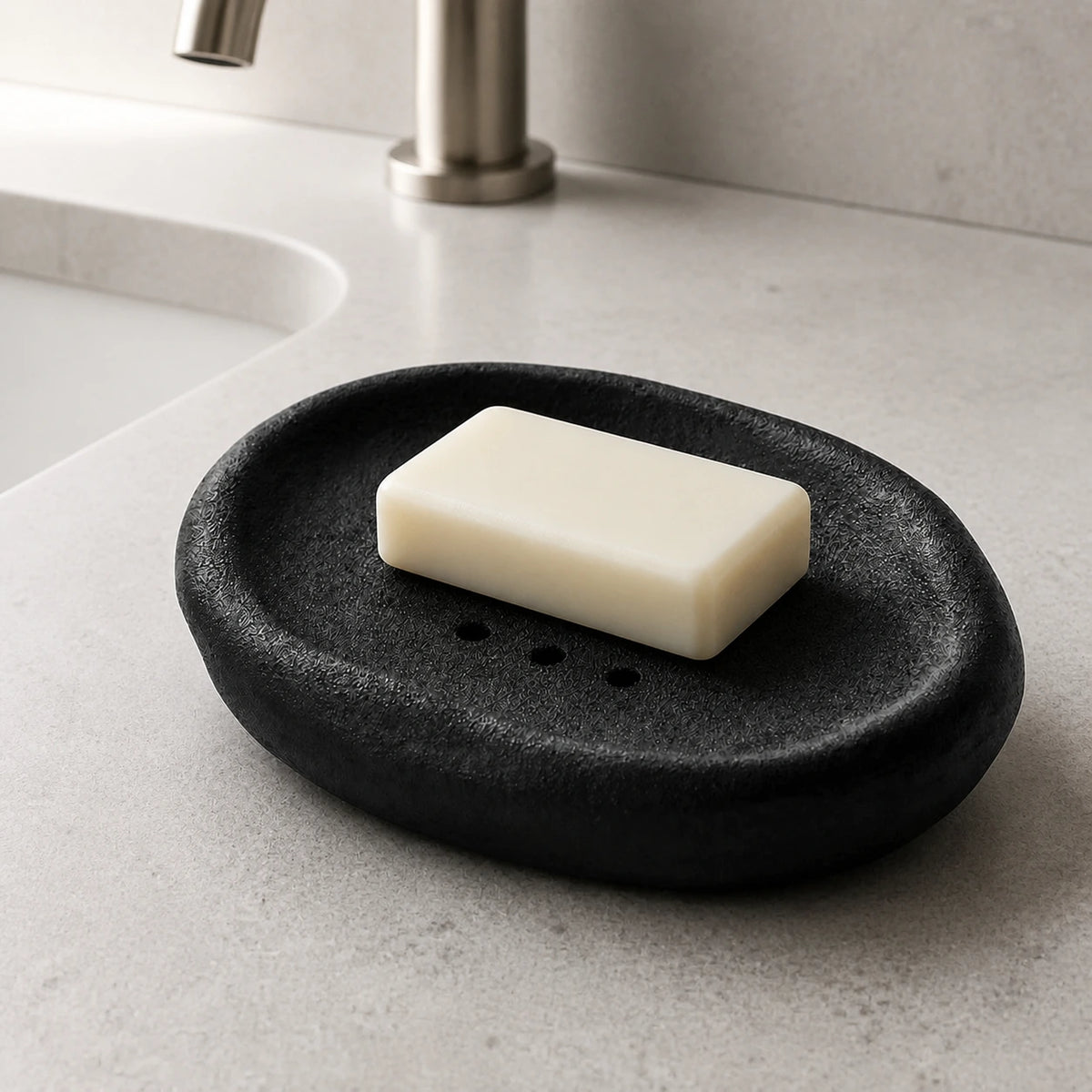 Black Vulcanized Obsidian ceramic soap dish holding an ivory bar beside a sink