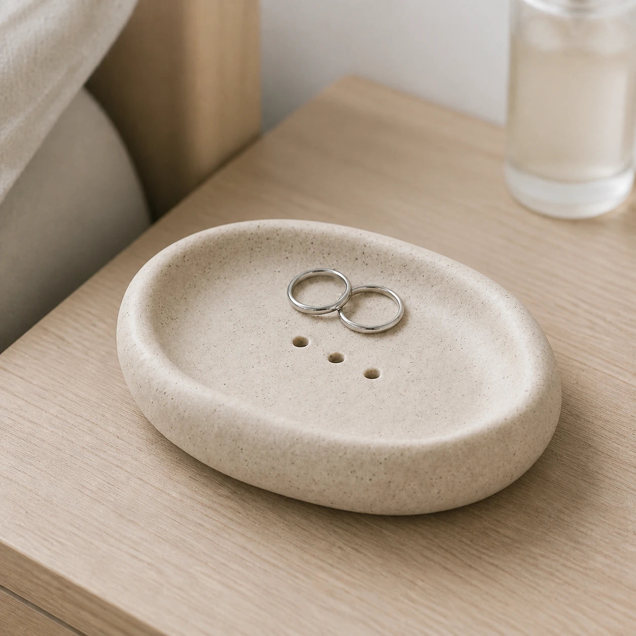 Warm Oat Sand ceramic dish holding two silver rings on a vanity