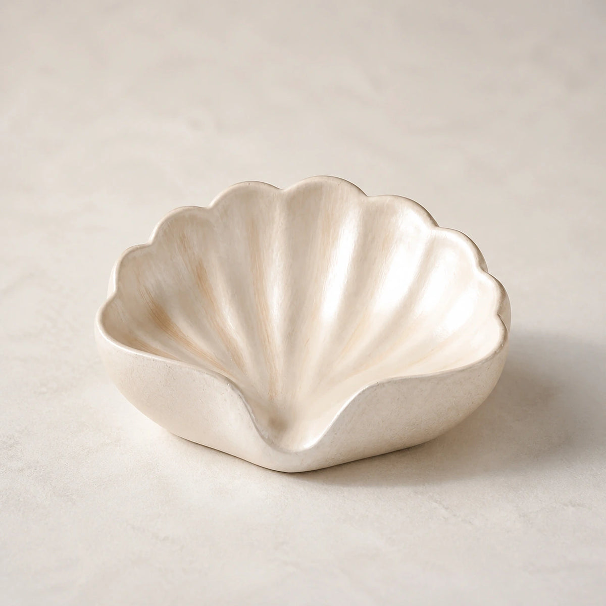 Champagne gold scallop-shell ceramic soap dish on a light stone background