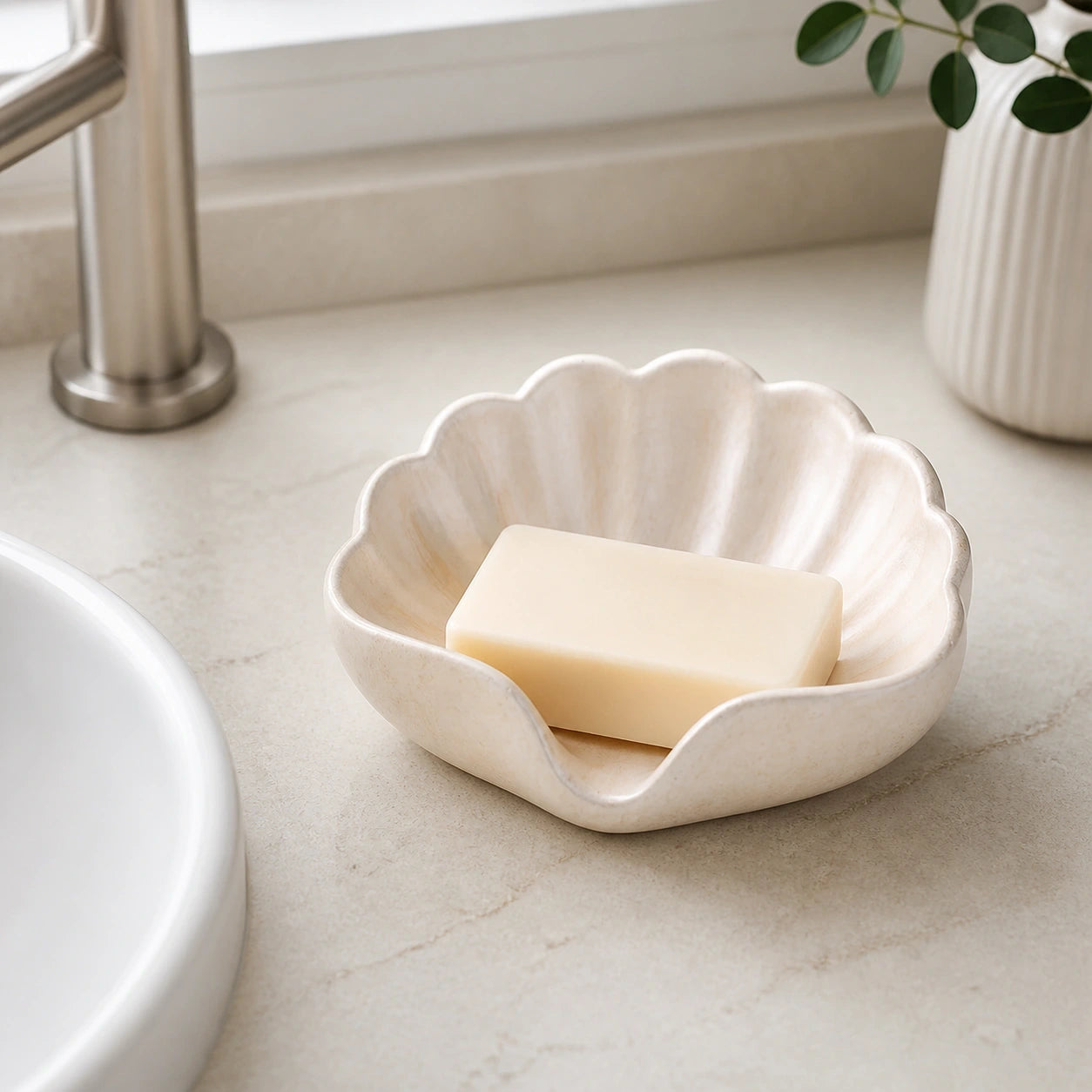 Champagne gold shell soap dish holding a bar of soap beside a bathroom sink