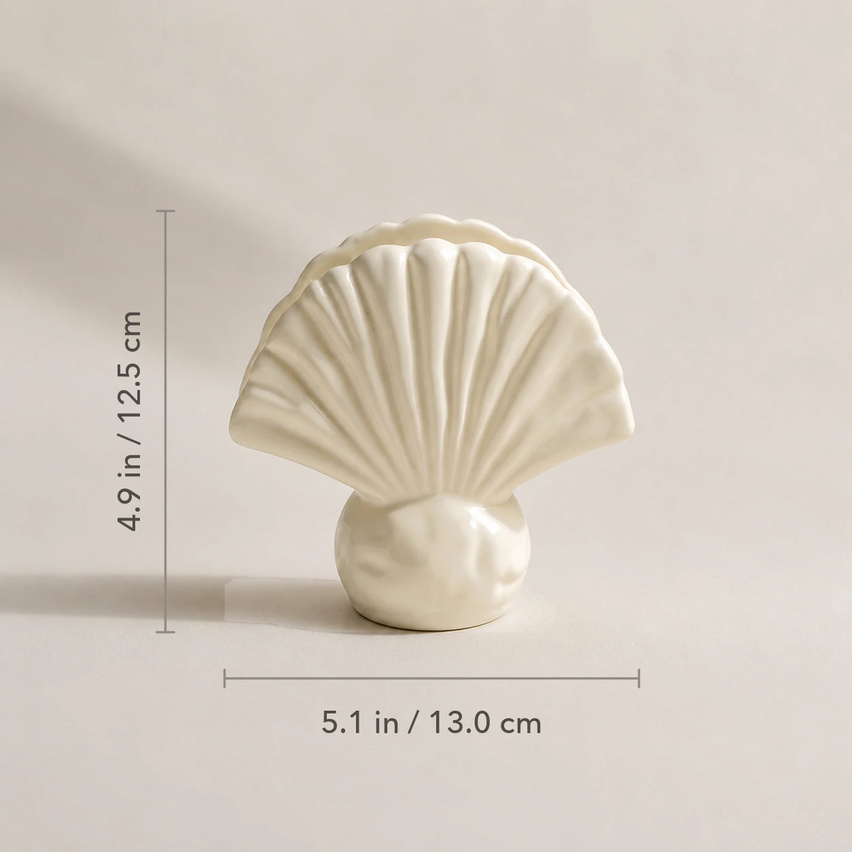 Elfenbeinfarbener Keramik-Serviettenhalter in Muschelform mit Maßen von 13 cm Breite und 12,5 cm Höhe