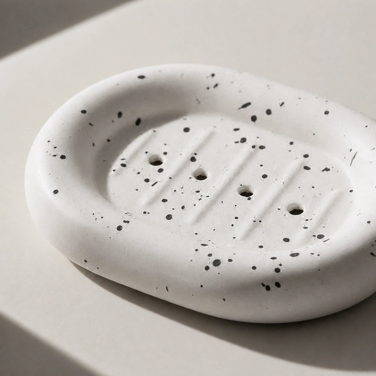Close view of ink splatter ceramic soap dish drainage holes and raised channels