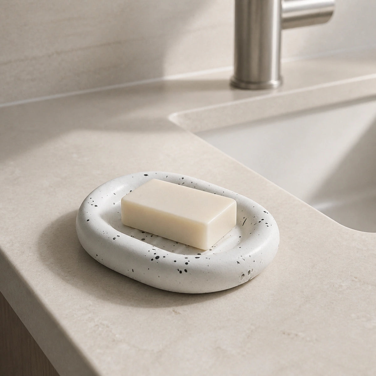 Ink splatter white ceramic soap dish holding a soap bar beside a bathroom sink
