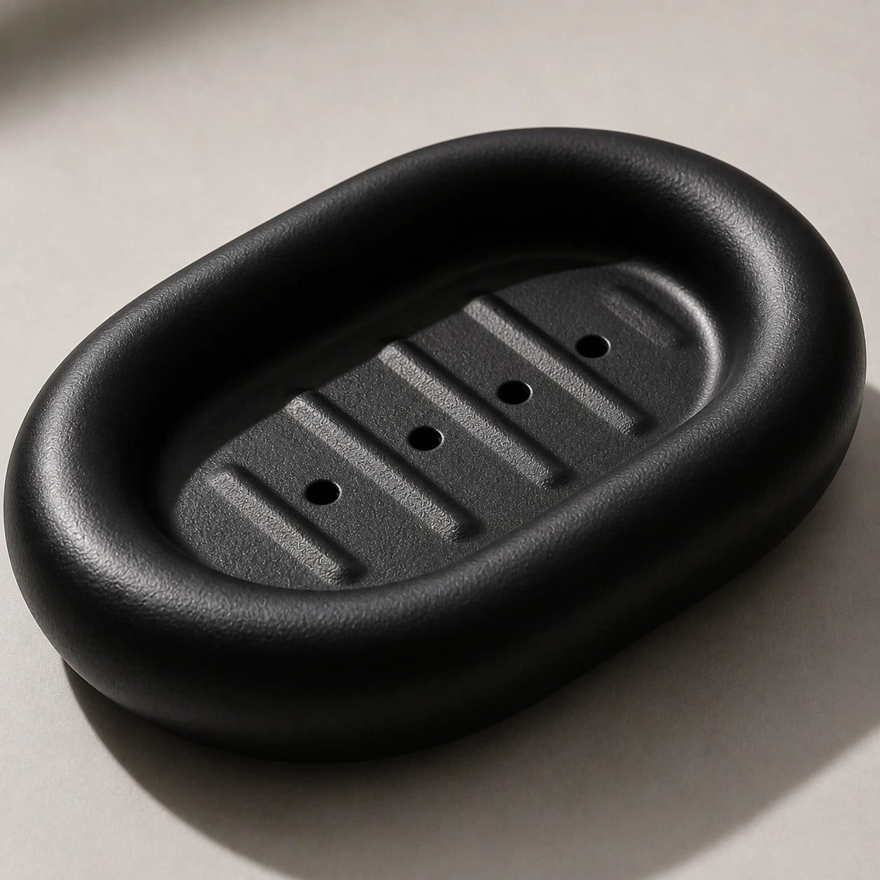 Close view of matte black ceramic soap dish drainage holes and raised channels