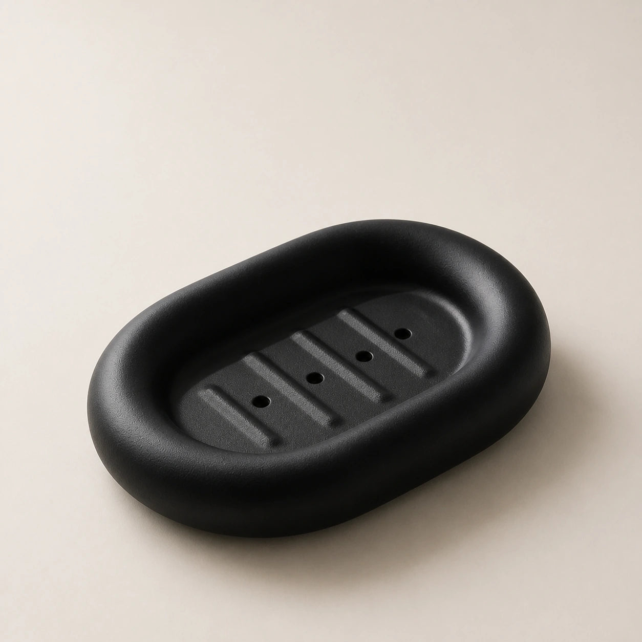 Matte black rounded ceramic soap dish on a light stone background